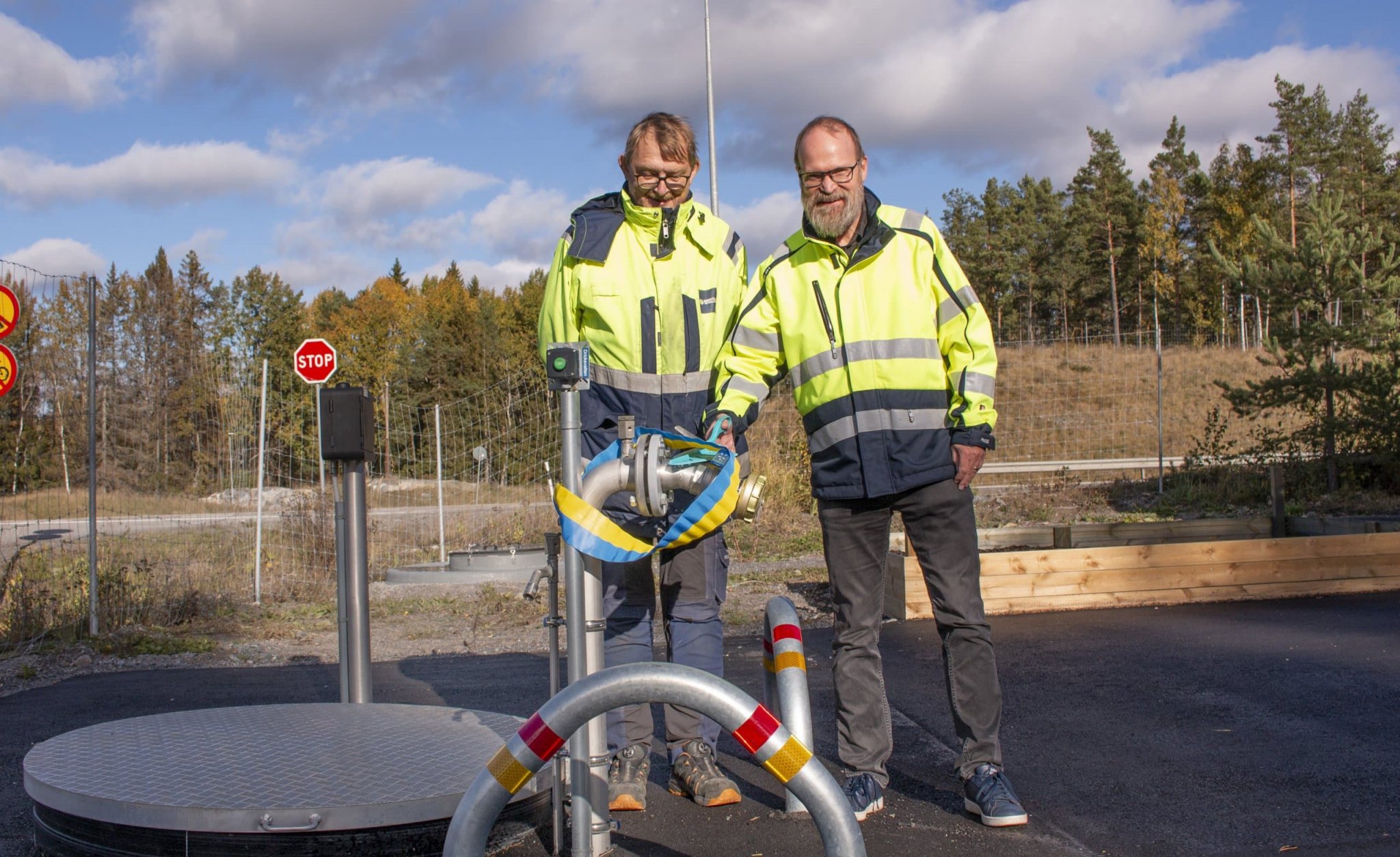 Två anställda klipper ett blågult band för att inviga vattenkiosken