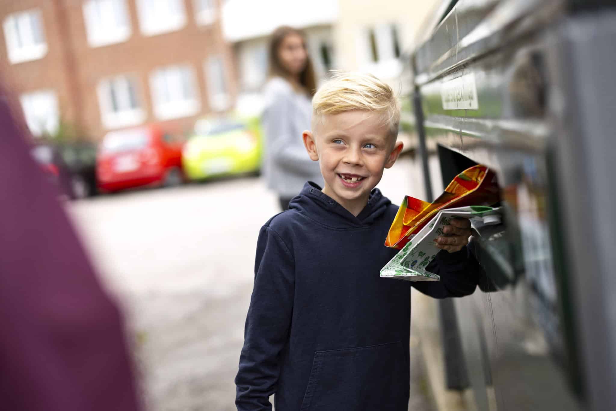 En pojke som lämnar förpackningar på en återvinningsstation