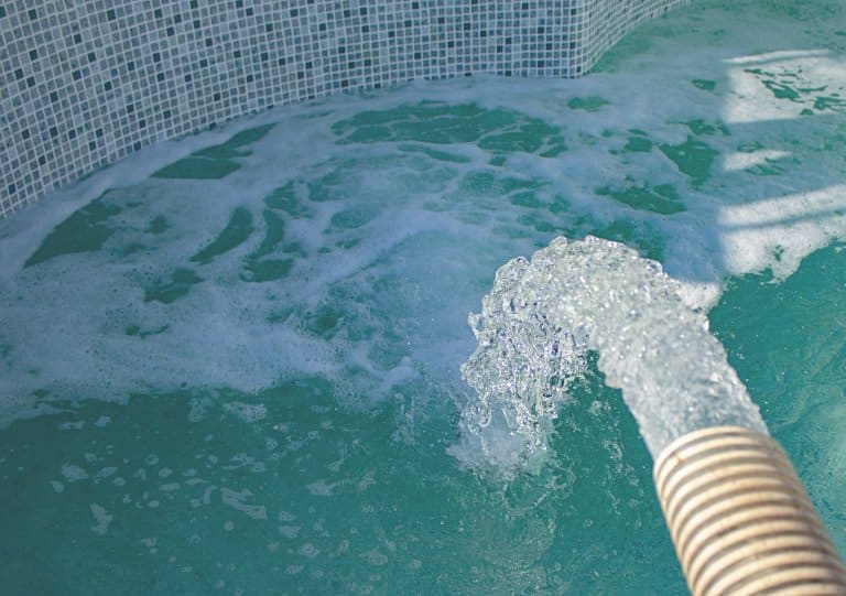 En slang med vatten som strålar ner i en pool.