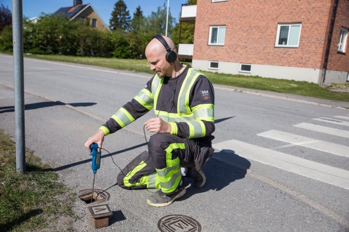 Varselklädd läcksökare lyssnar efter en läcka med ett speciellt verktyg, en lyssnare 