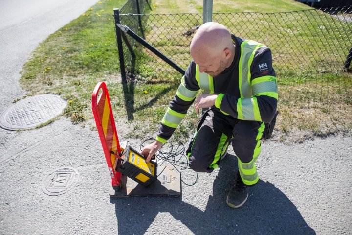 Varselklädd läcksökare ställer en korrelator vid en ventilbrunn