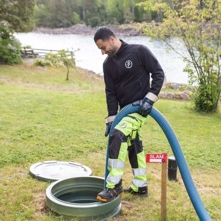 Slambilschaufför tömmer en brunn vid vattnet