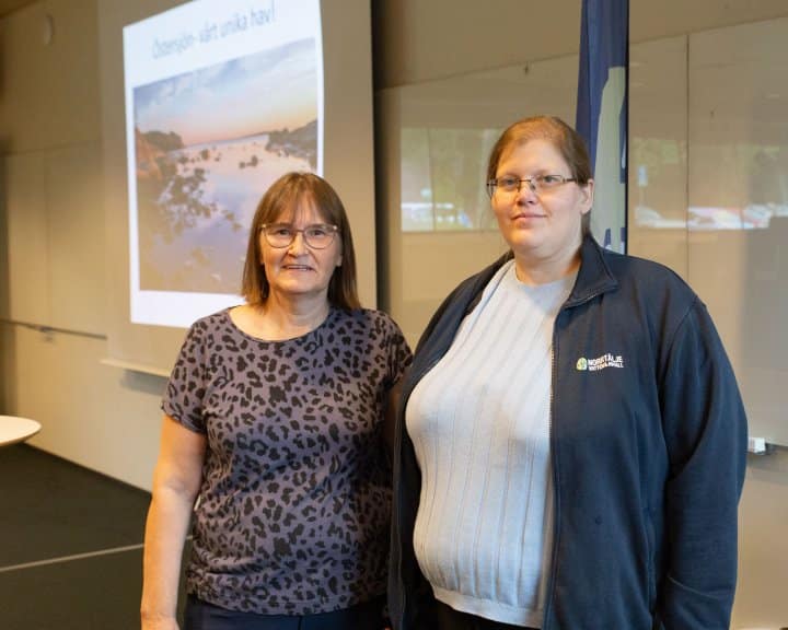 Kristiina och Emma står framför en powerpoint-presentation