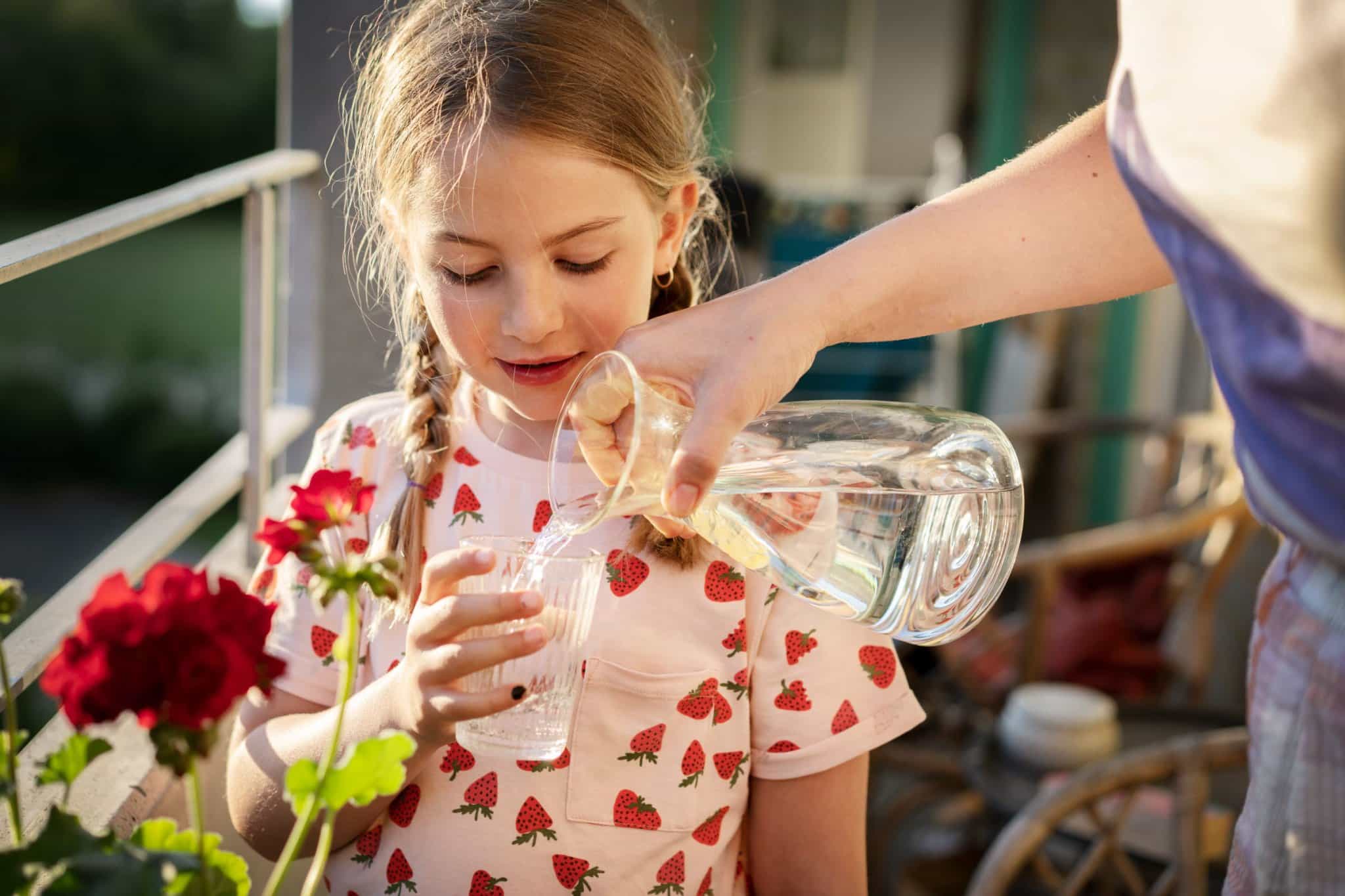 Hållbar vattenanvändning - flicka får vatten i glas.