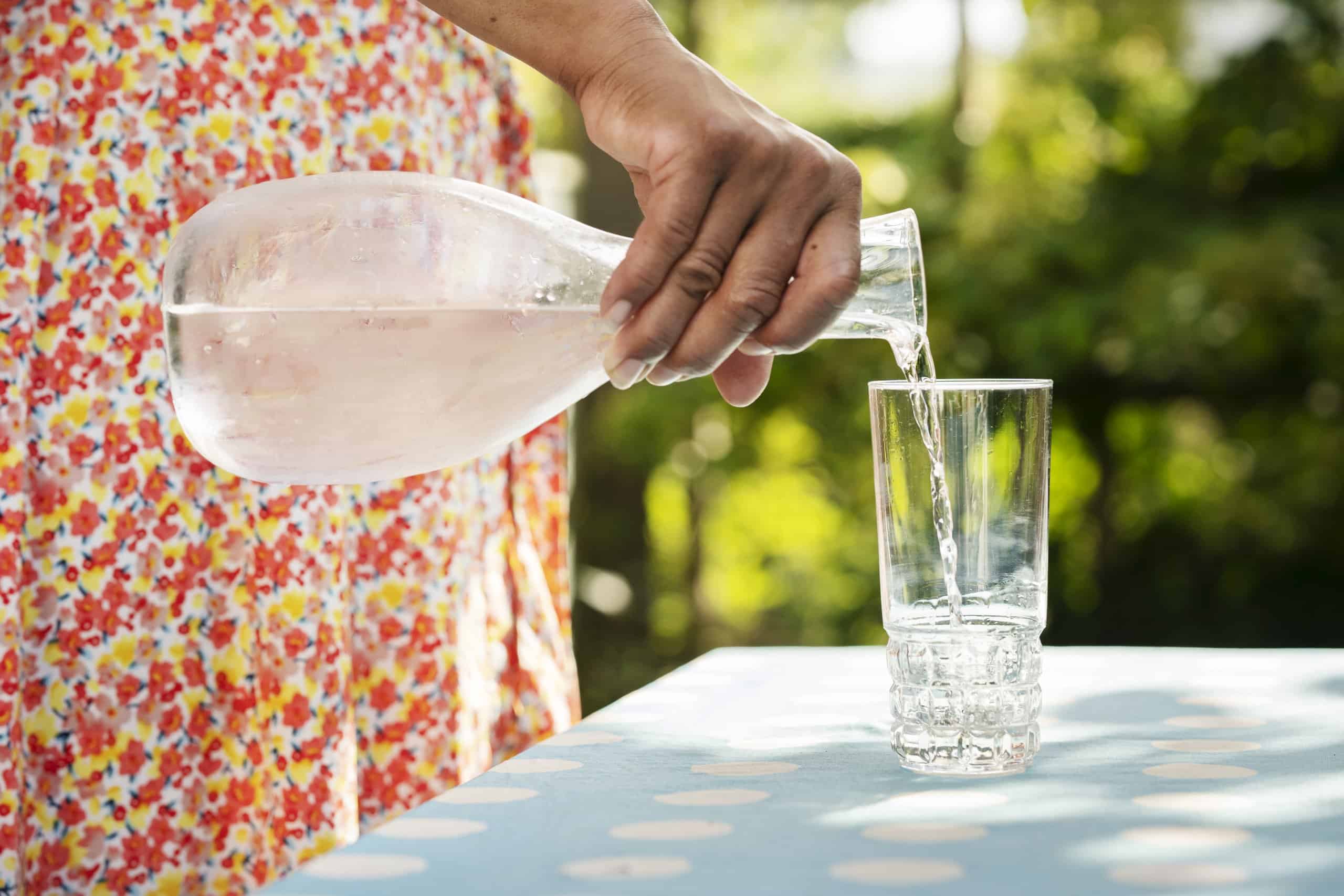 Kvinna häller upp vatten från karaff i glas